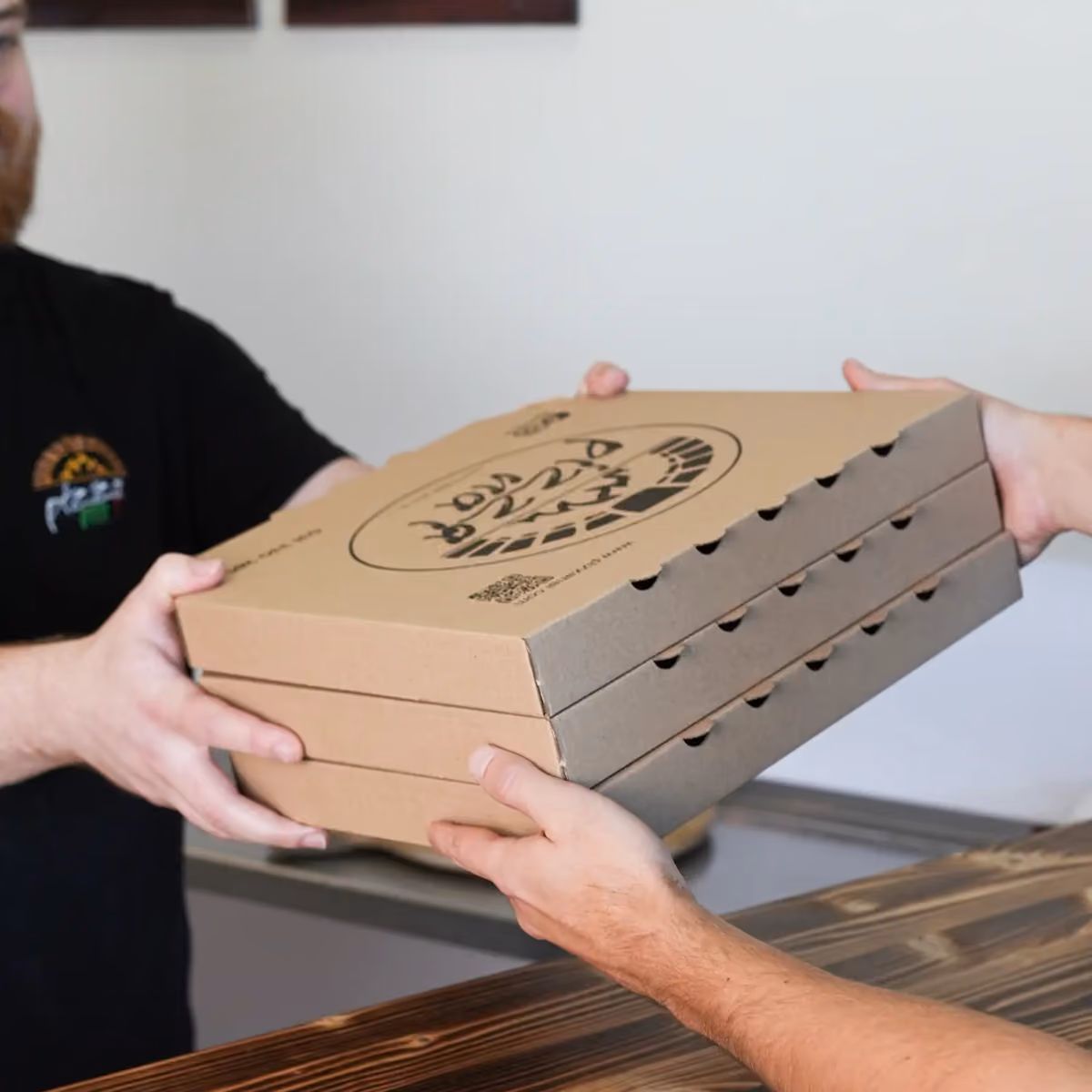 Gast nimmt drei Pizzakartons am Tresen entgegen