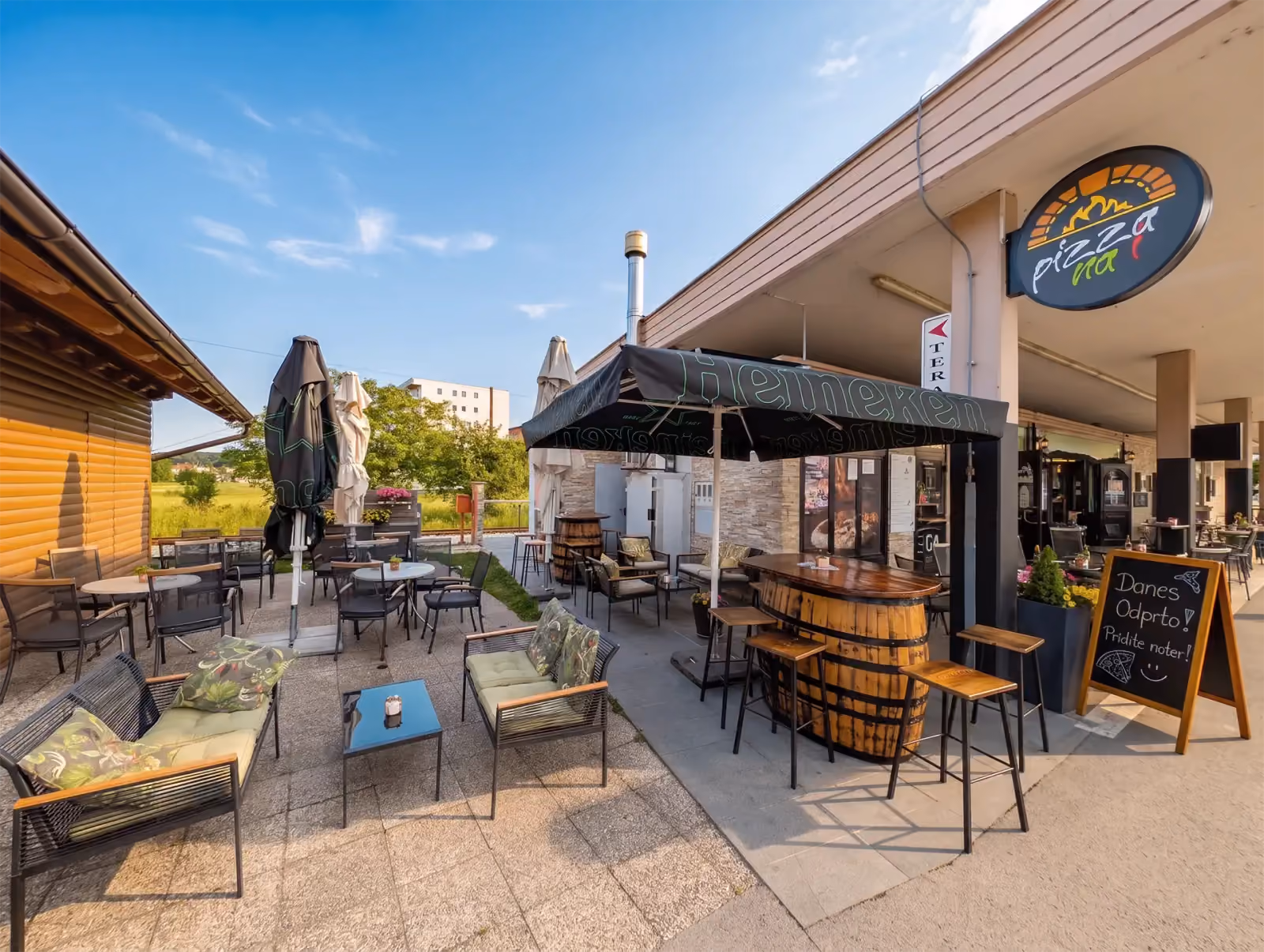 Terrasse des Lokals in Radenci mit Tischen, Sonnenschirmen und dem Pizza-na-i-Schild